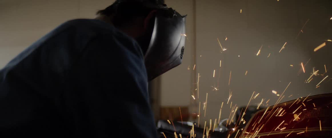 A man is using a grinder on a car