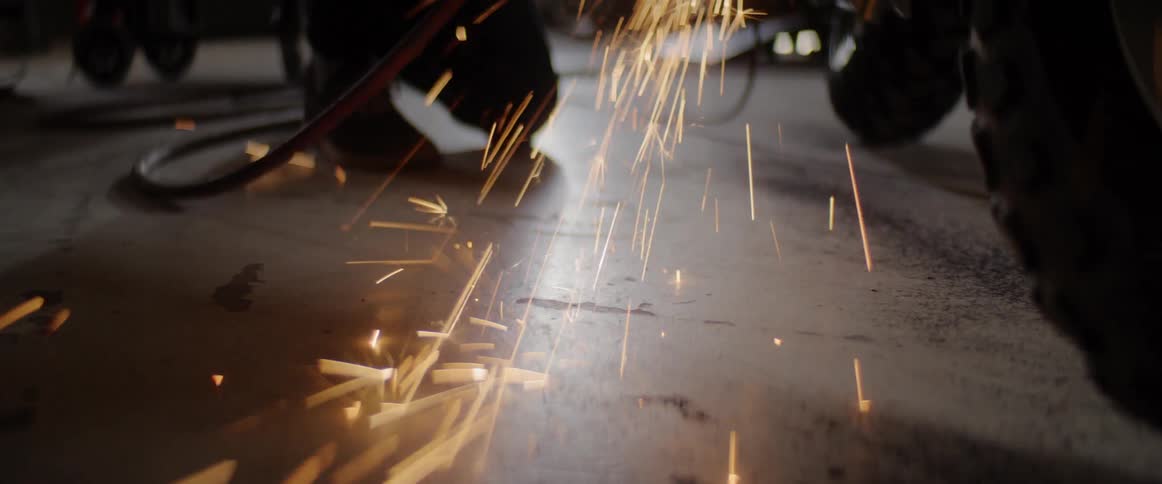 Worker cuts metal with grinder in an auto body shop