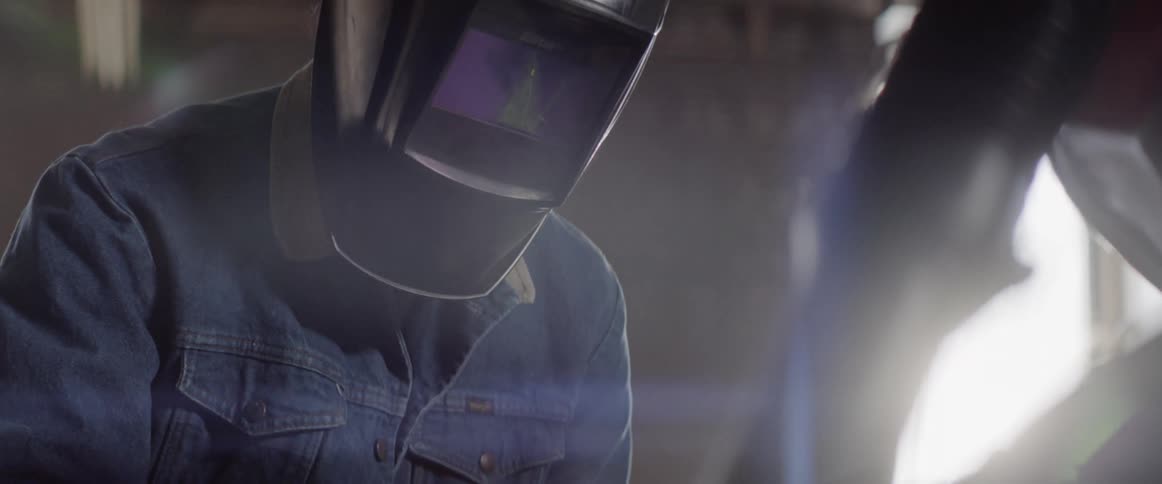 Man wearing a motorcycle helmet looks down in the auto body shop