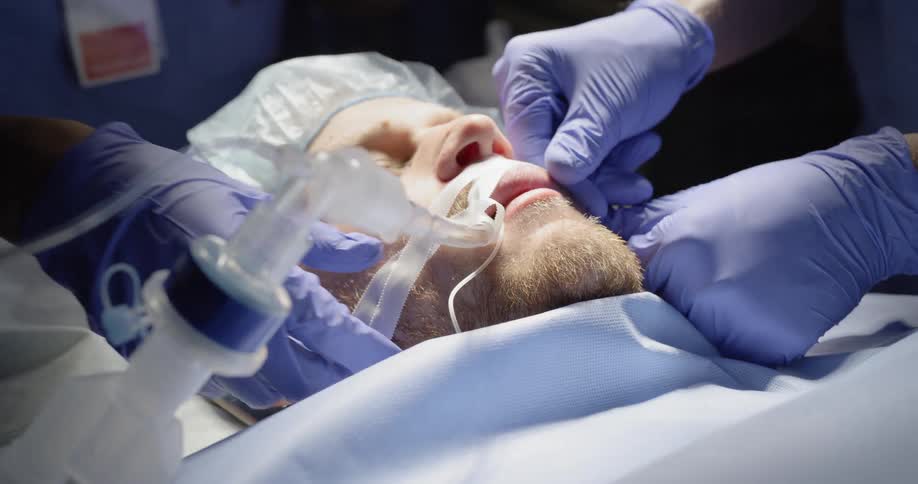 A patient lies intubated on a table as medical staff tape the tube in