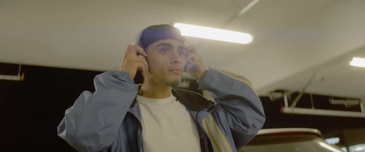 Man exits car in parking garage and puts on headphones