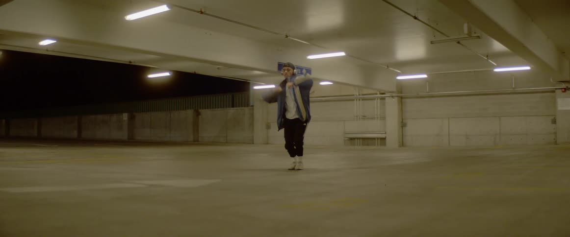 A man is dancing in an empty parking lot