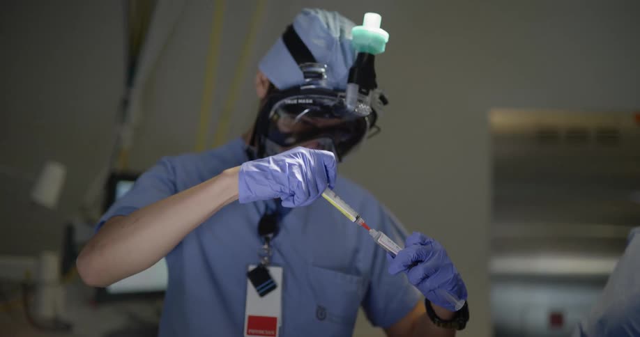 A medical professional using a syringe to extract a liquid from a tube