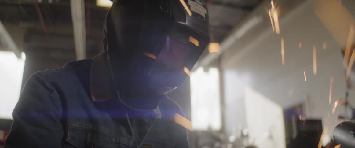 Man using power tool to cut metal spraying sparks everywhere