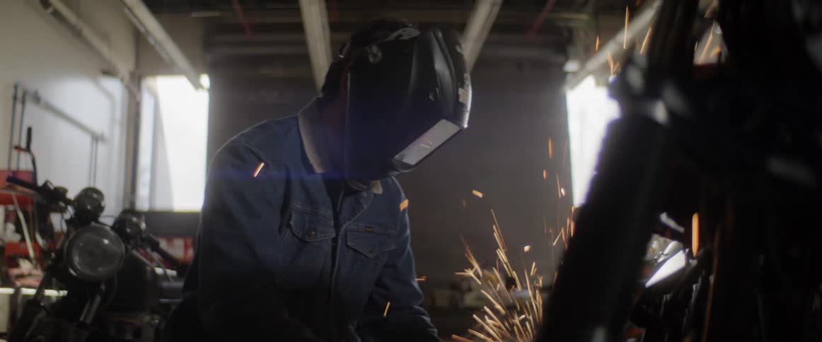 A person grinds metal in a shop