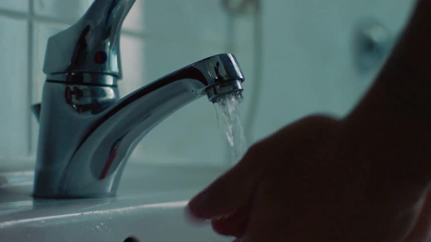 A person washes their hands at a sink