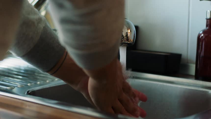 Man washes and cleans his hands in the kitchen