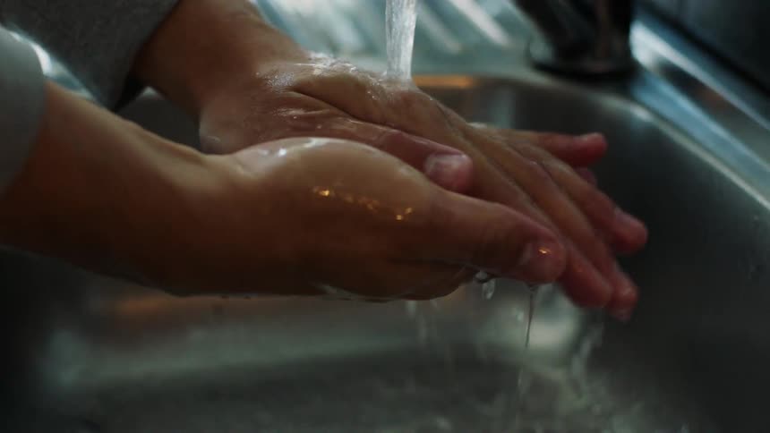 A person washing their hands in the sink