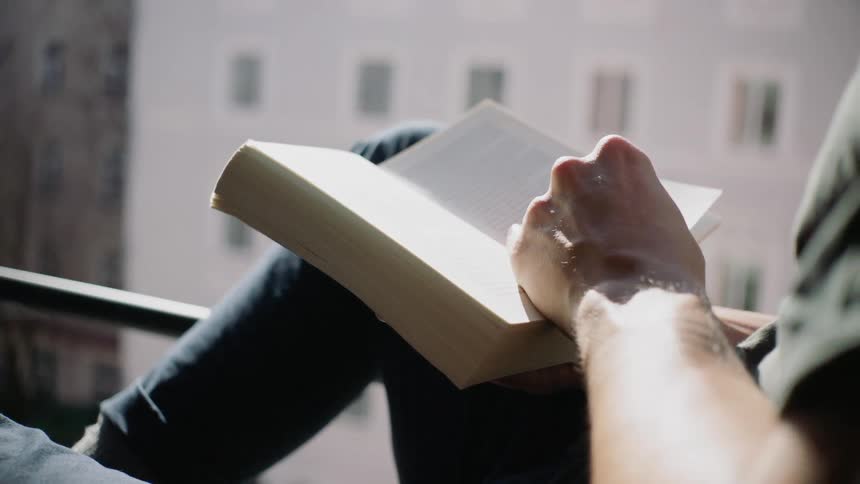 A person flips through a book by the window