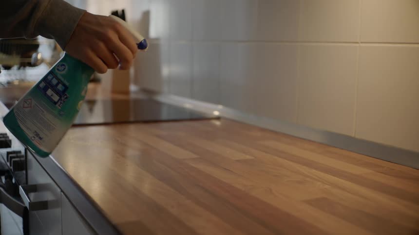 A man sprays a counter with cleaner