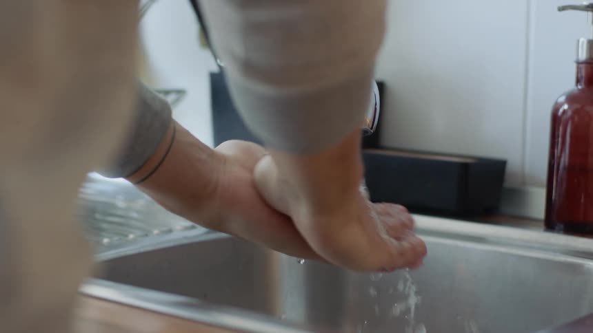 A woman washes her hands at a sink
