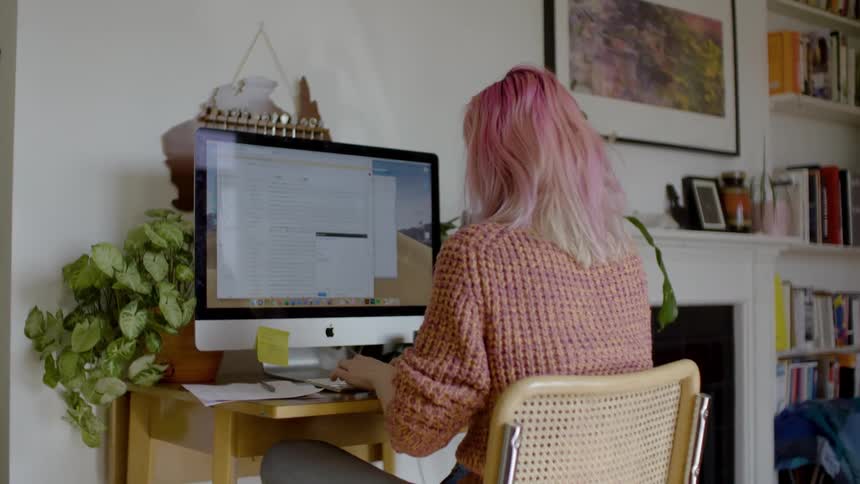 Young woman works at desktop computer at home
