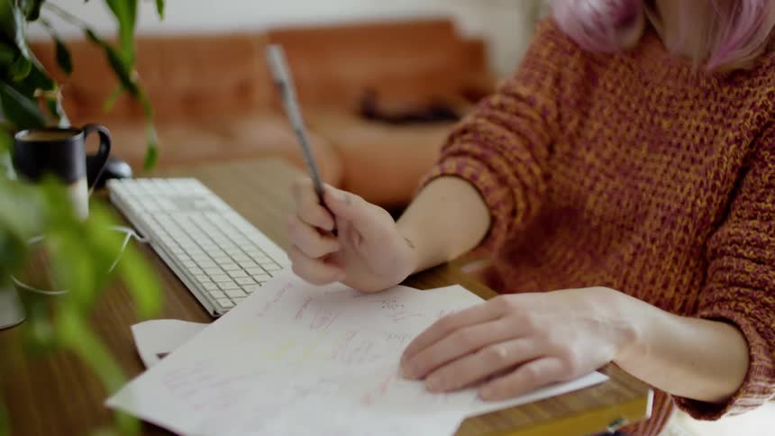 Female working from home on a conference call taking notes