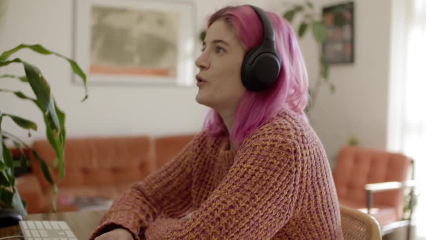 Woman wearing headphones sits in front of computer while having a video conference