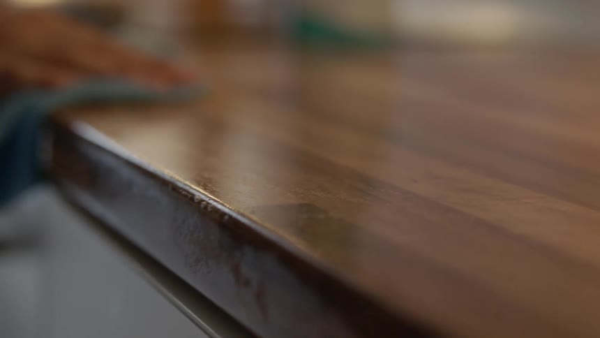 Person dusts the table top with a blue cloth