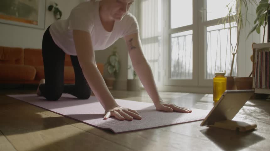 Woman practices yoga on living room floor at morning