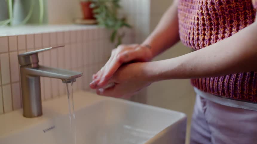 Female washing her hands with soap in the bathroom