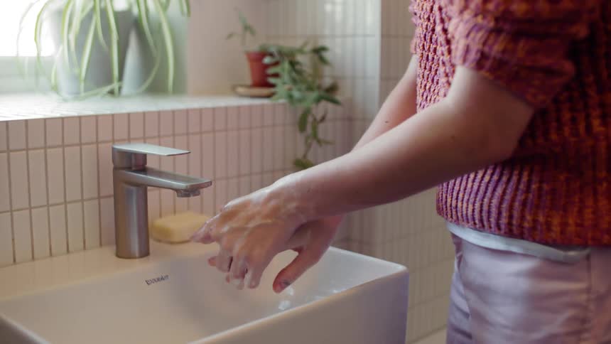 A person thoroughly washing their hands in a square sink