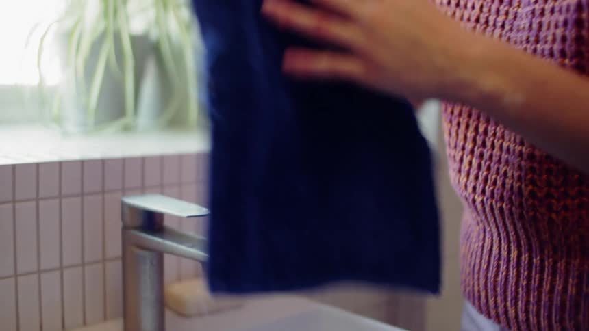 A woman washes her hands in a bathroom sink