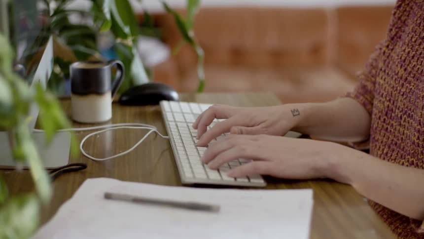 Woman sitting at the desk types on keyboard in her room during daylight