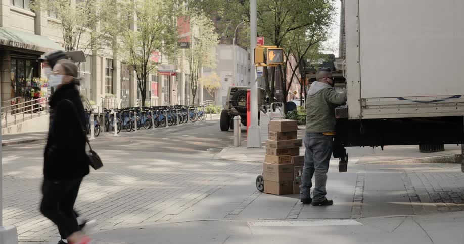 A delivery driver is unloaded boxes to a handcart