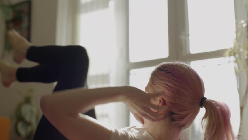 A women does crunches touching her elbow to opposite knee on the floor at home