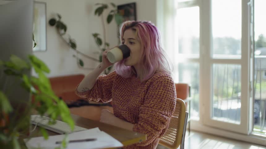 Woman having video conference on computer and drinking coffee