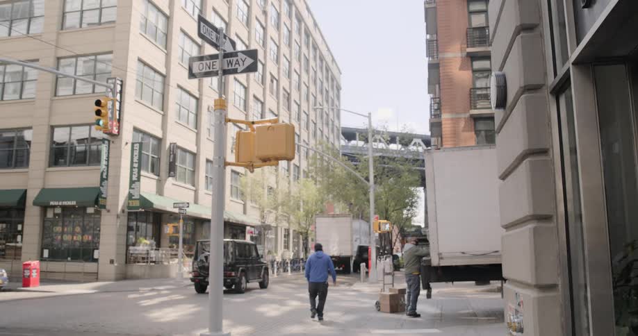 Pedestrian walks past man unloading semi trailer on city street