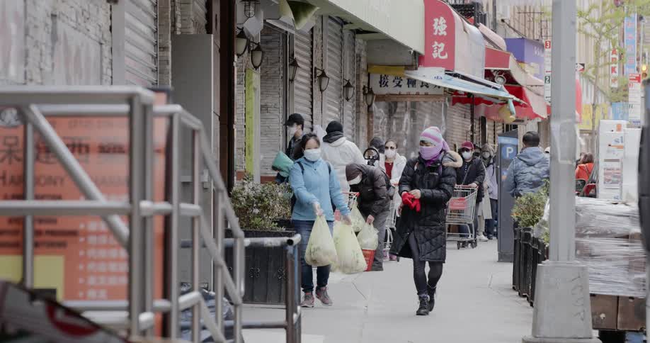 Two asian women wearing face masks walk down city sidewalk