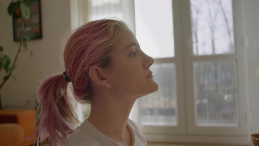 Young woman with pink hair sits up and faces to side