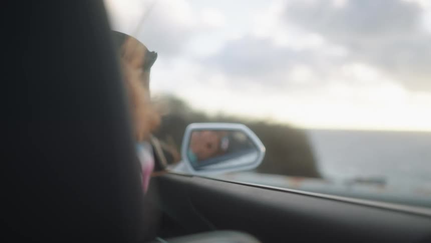 A child rides in a convertible next to the ocean