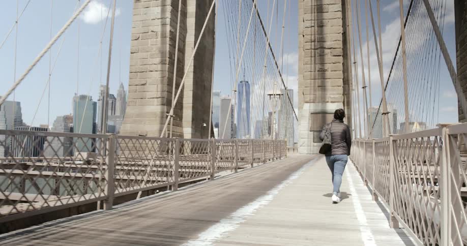 Woman walks pedestrian walkway brooklyn bridge new york