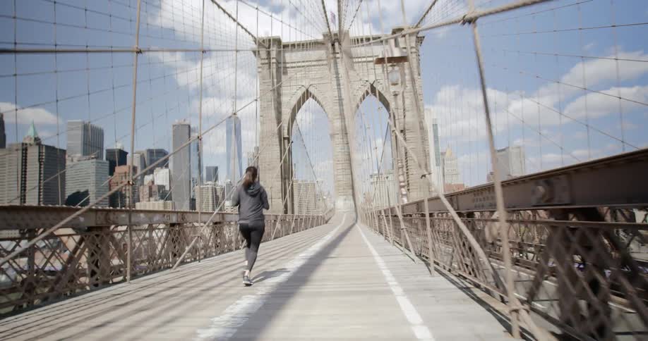 Woman jogs on bridge in new york at day