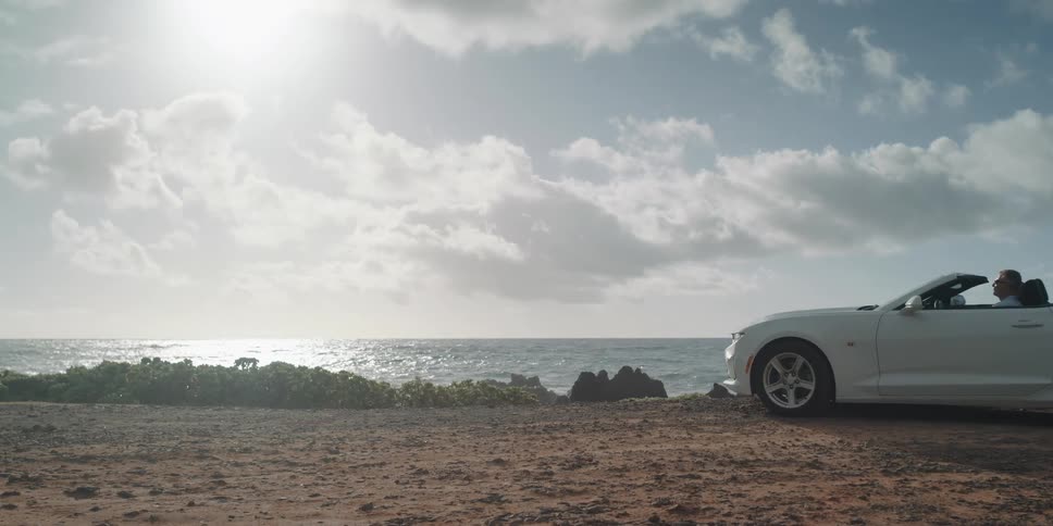 White convertible parking at cliff edge overlooking the coast