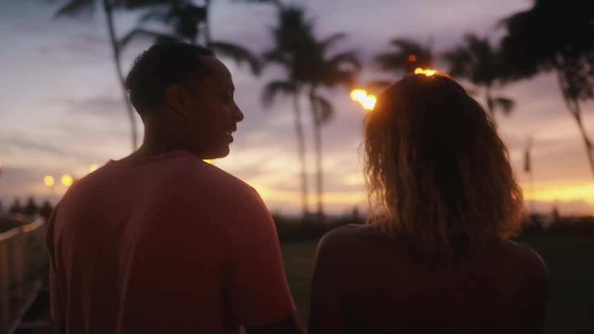 Couple walks holding hands to a party on the beach