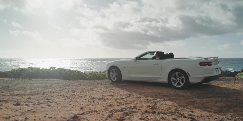 A man and woman are driving a car by the ocean coast