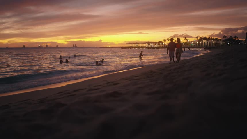 A couple walks beside the ocean coast line during sun up or sun down