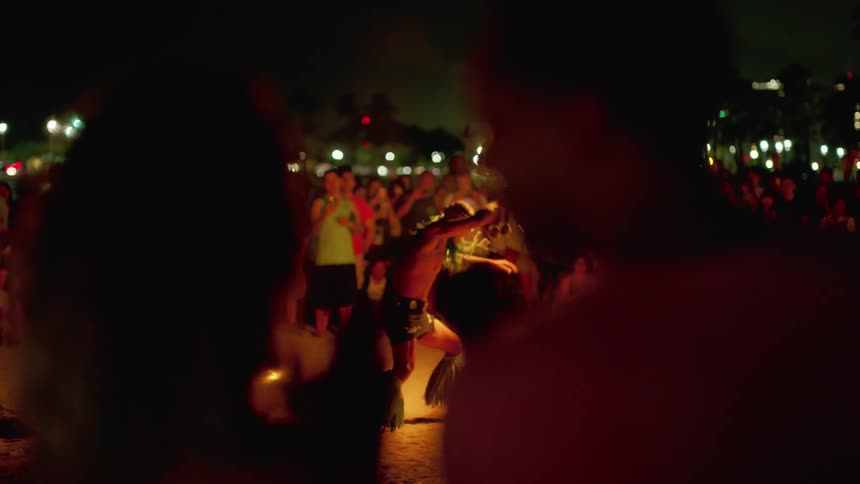 A male performer swings a flaming baton for a crowd