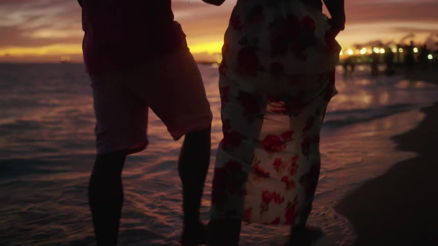 A man and woman walk the ocean coast line together at night