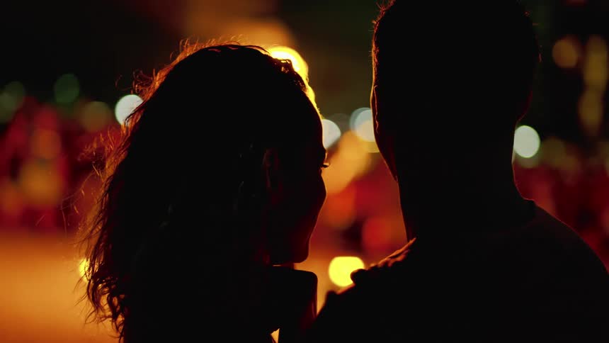 Couple in silhouette in front of luau