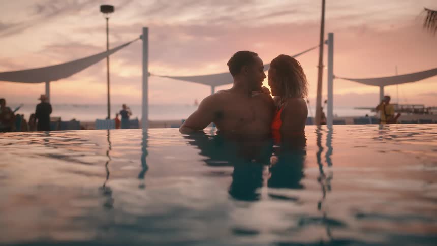 Man and woman embrace as they stand in the water