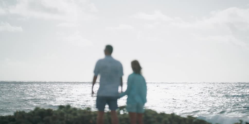 Couple standing at end of cliff looking out to the ocean on a windy day