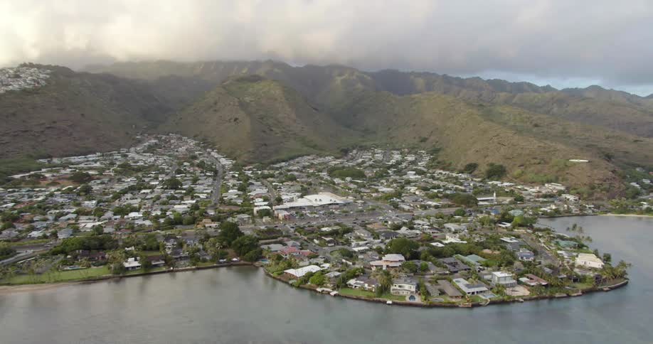 A small town on the coast at the bottom of large grassy hills