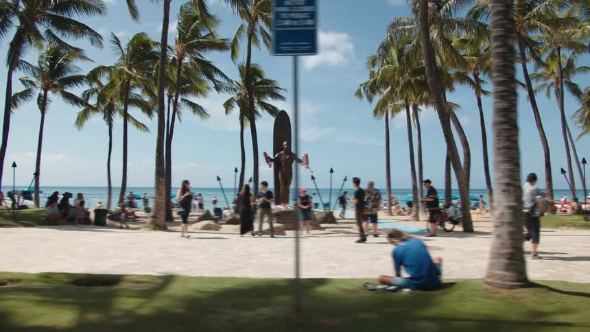 Driving by a crowded beach where people are walking and hanging out
