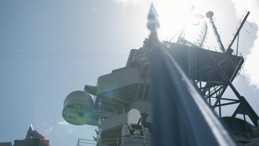 Flags in the wind on a sunny day in front of a ship tower with antenna and satellite