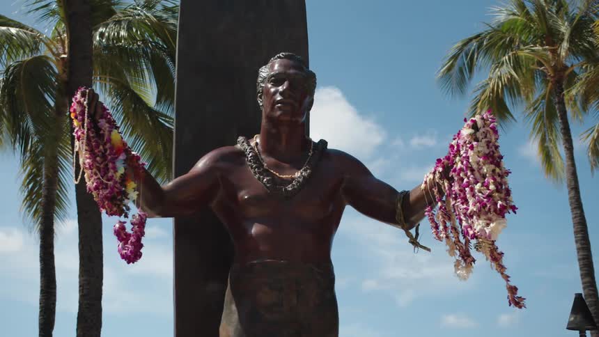 Bronze male statue holding flower leis in a tropical destination