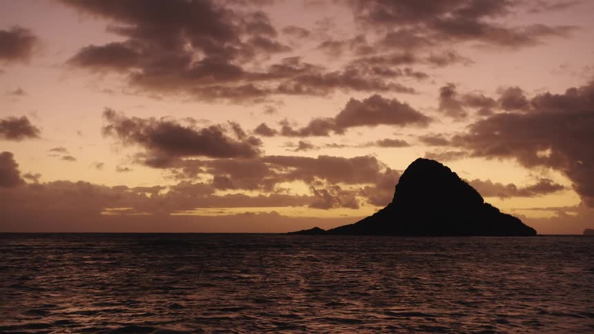 Small rocky island silhouetted against sunset