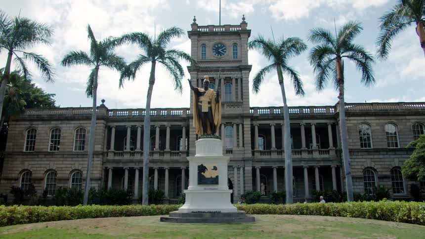 A statue in front of a building with a clock tower