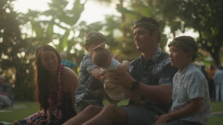 A family sitting together in the grass during a celebration