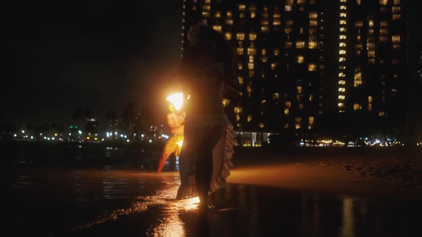 Traditional hawaiian fire dancers on the beach at night